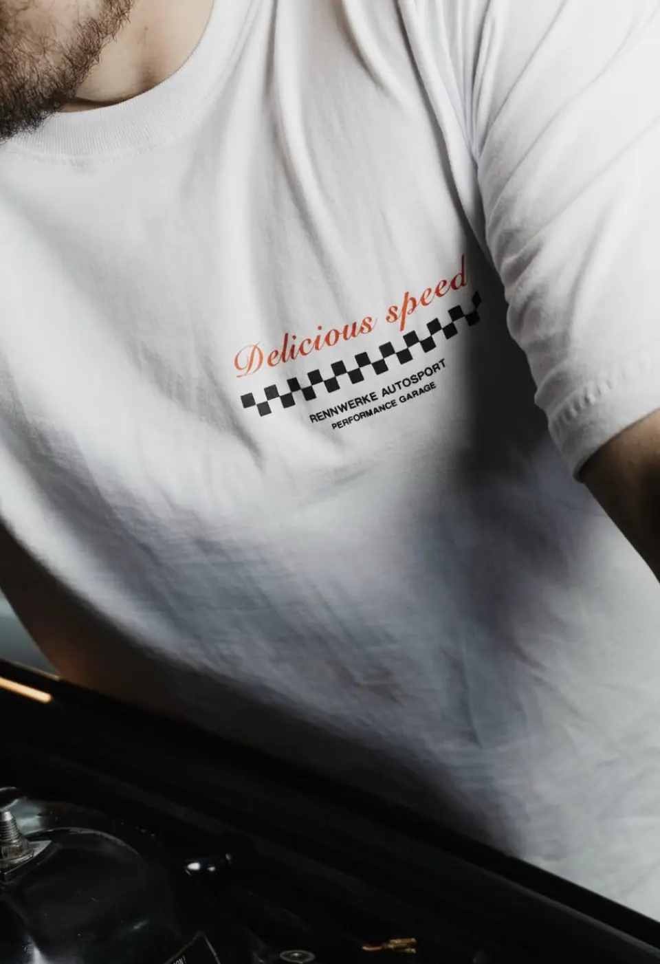 Frente da camiseta com a frase Delicious speed e faixa quadriculada RennWerke Autosport