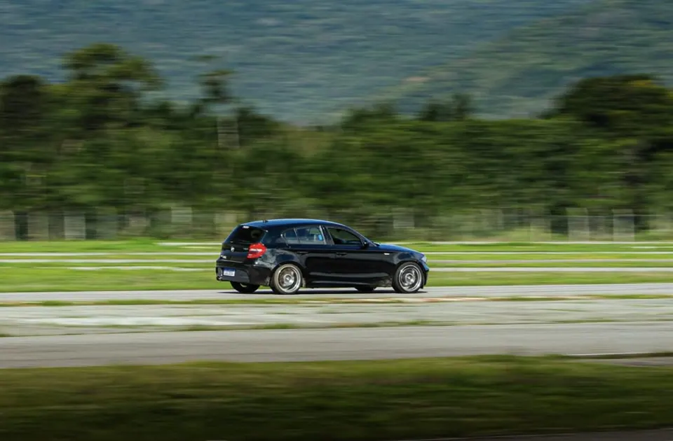 BMW Série 1 preta acelerando na reta da pista